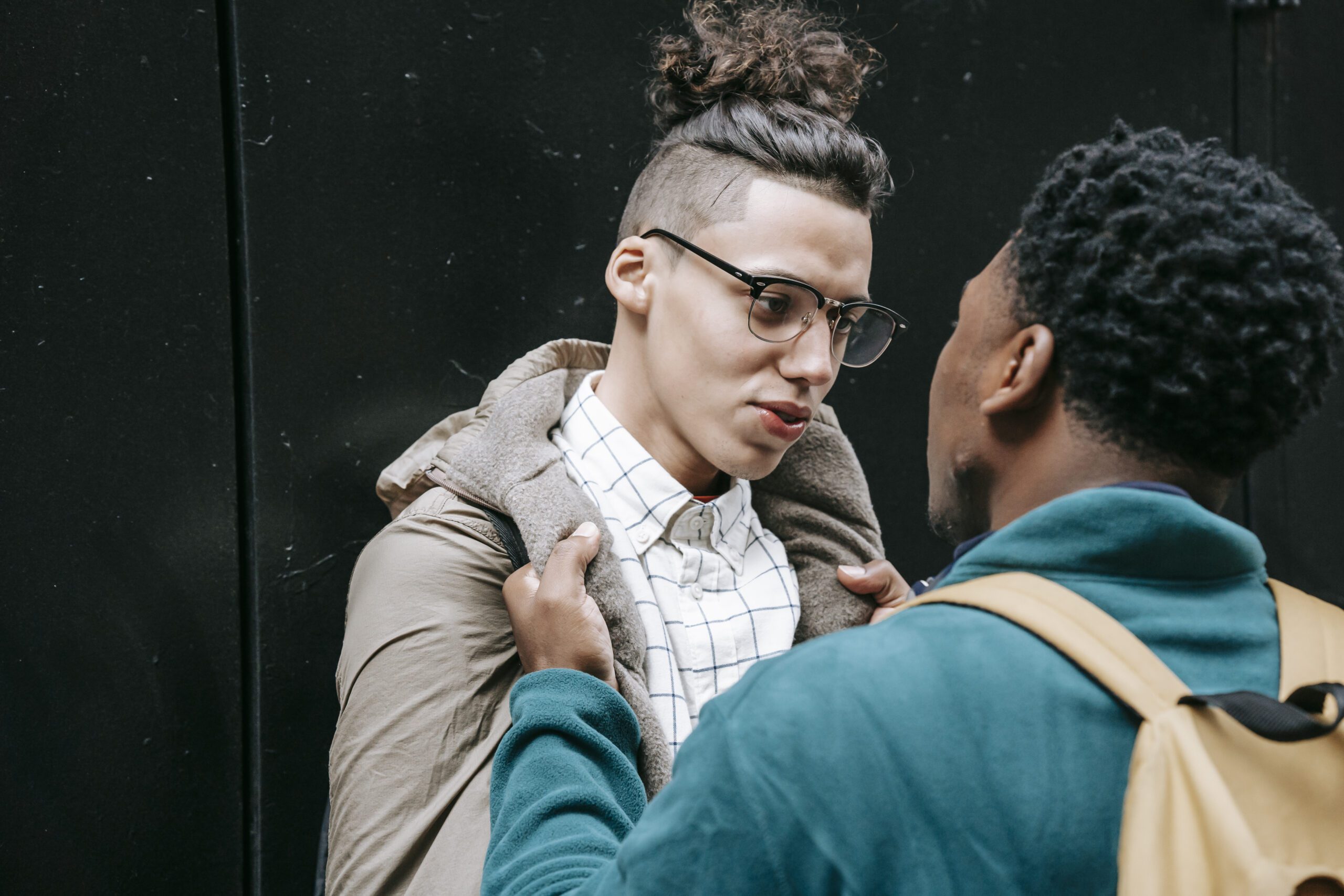 Nervous young black man grabbing collar of male groupmate on street