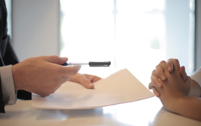 Crop businessman giving contract to woman to sign